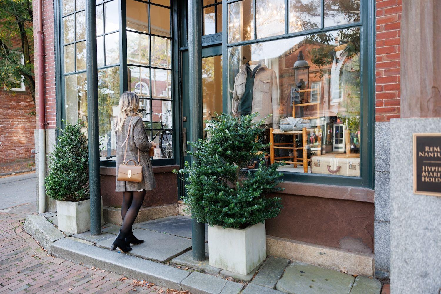 Woman window shopping at store front on cobblestone street.