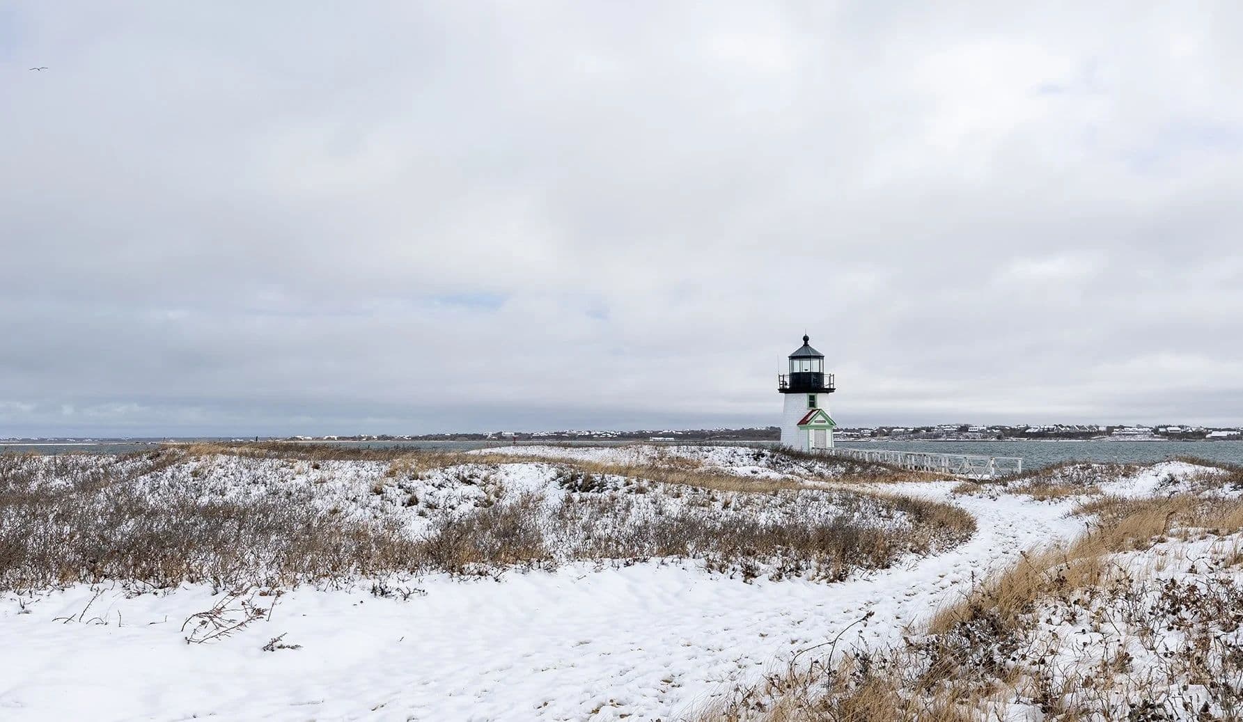 Snowy beach with lighthouse in the background