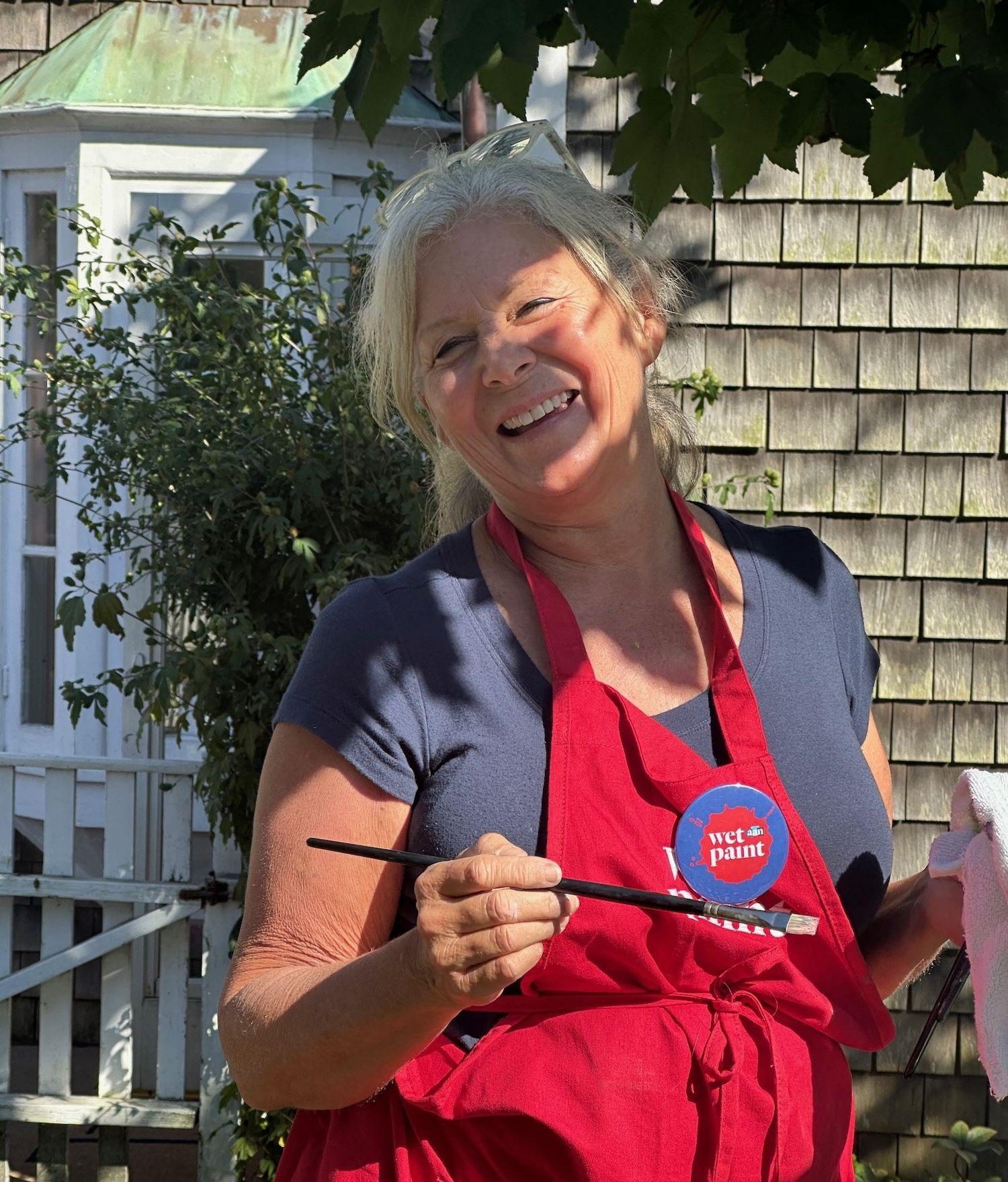 Woman in smock with paint brush smiling