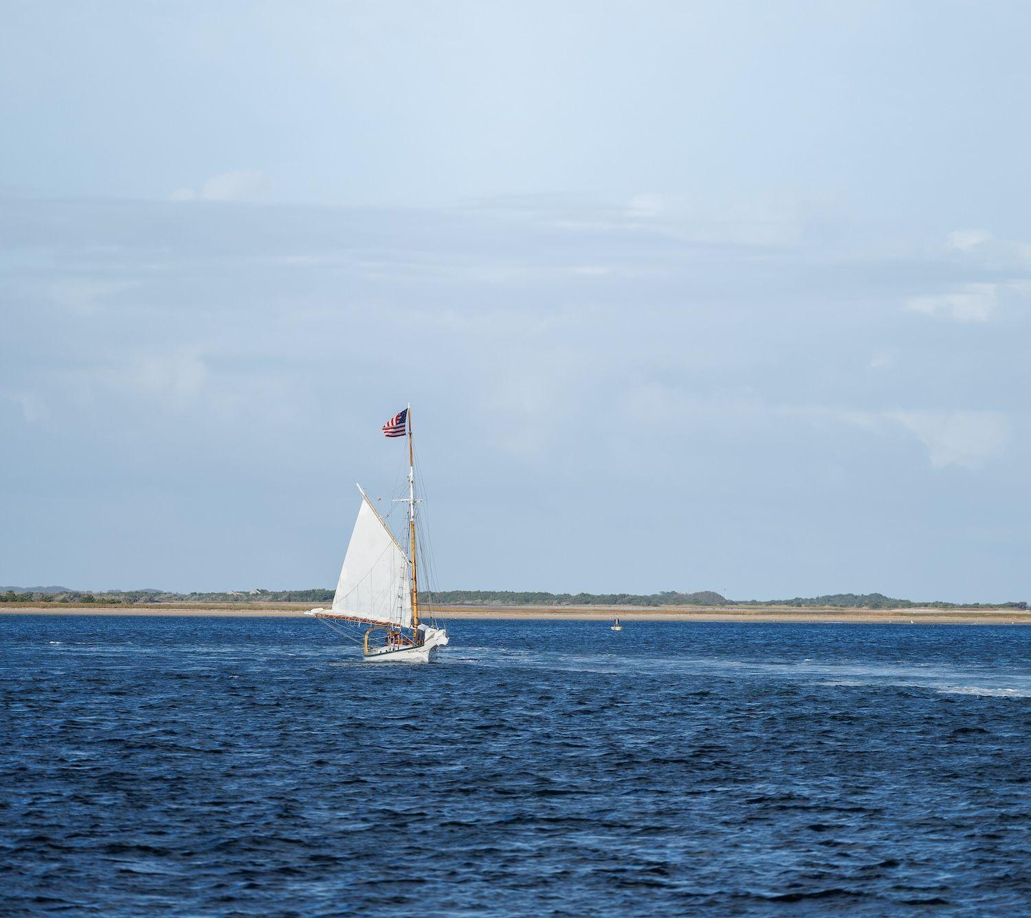 Sailboat with American flag in blue water.