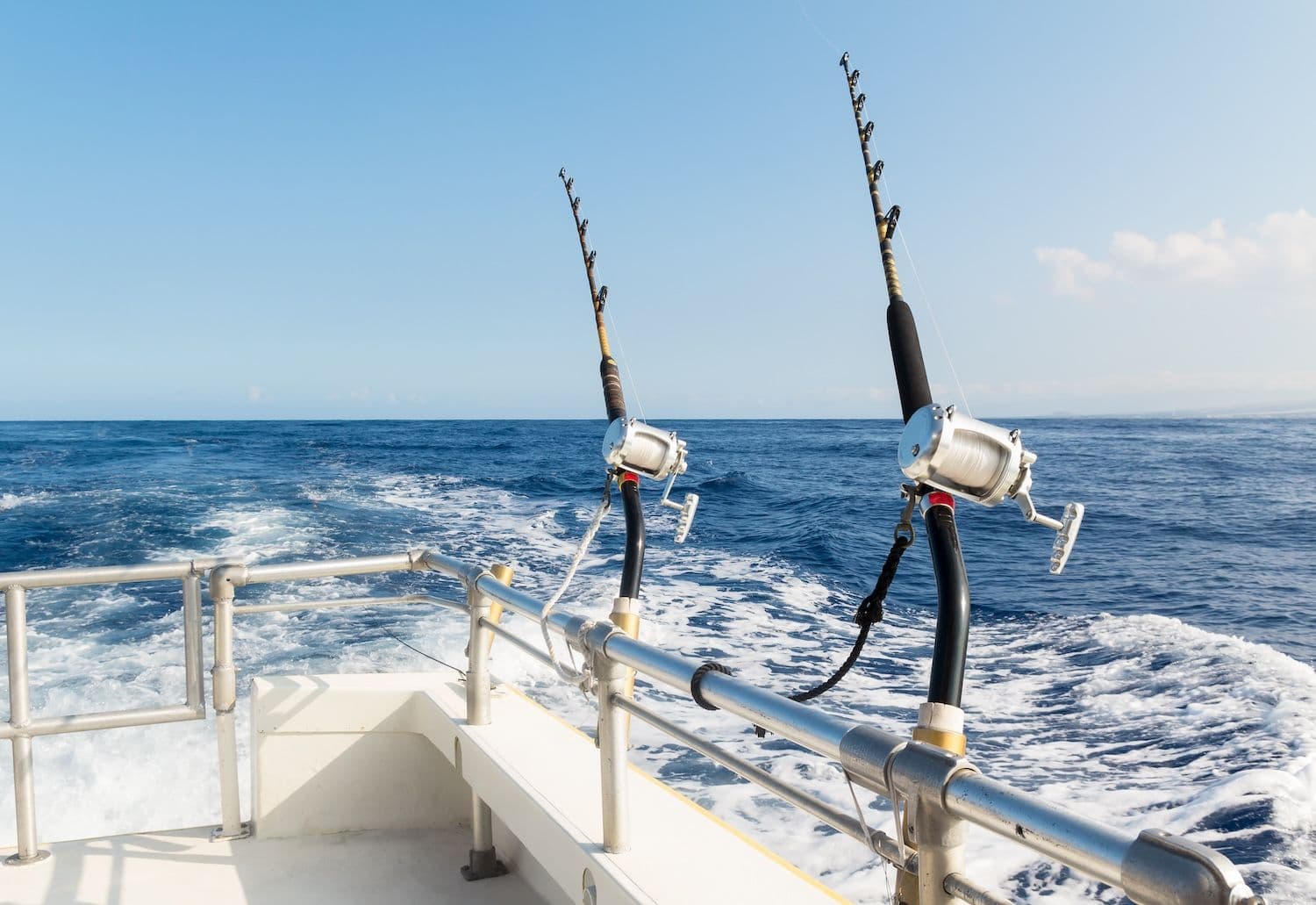 Fishing poles attached to boat with fishing lines going into water.