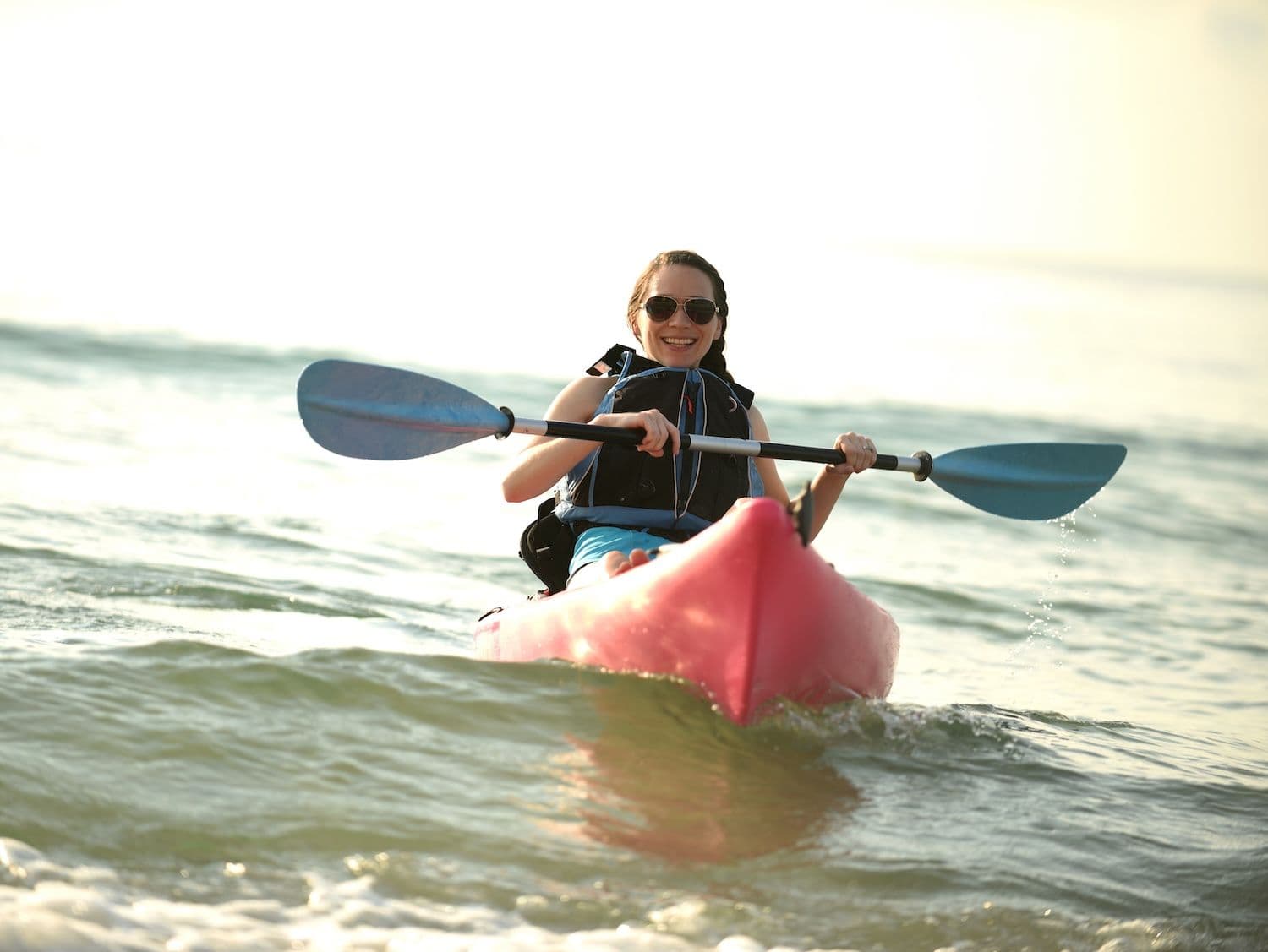 Woman kayaking in calm surf.